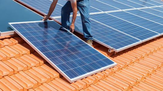 Solar system technician installing a solar panel on the roof
